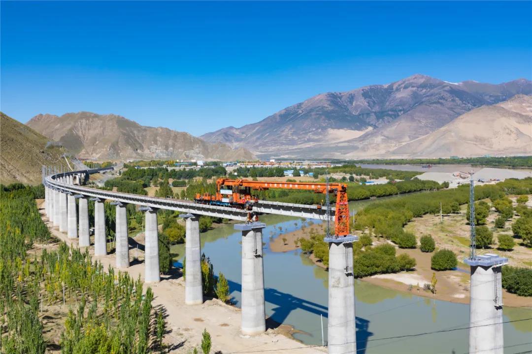 拉林鐵路90%以上路段位于3000米以上的高海拔地區，既有高原高寒缺氧、生態脆弱的嚴酷自然環境，更面臨頻發多變的風積沙、冰磧層、強巖爆、高地溫和軟巖大變形等復雜地質環境。其中，橋梁120座，隧道47座，橋隧比高達74.66%。全線還16次穿越雅魯藏布江，工程施工極其困難。圖為拉林鐵路程巴特大橋T梁架設。