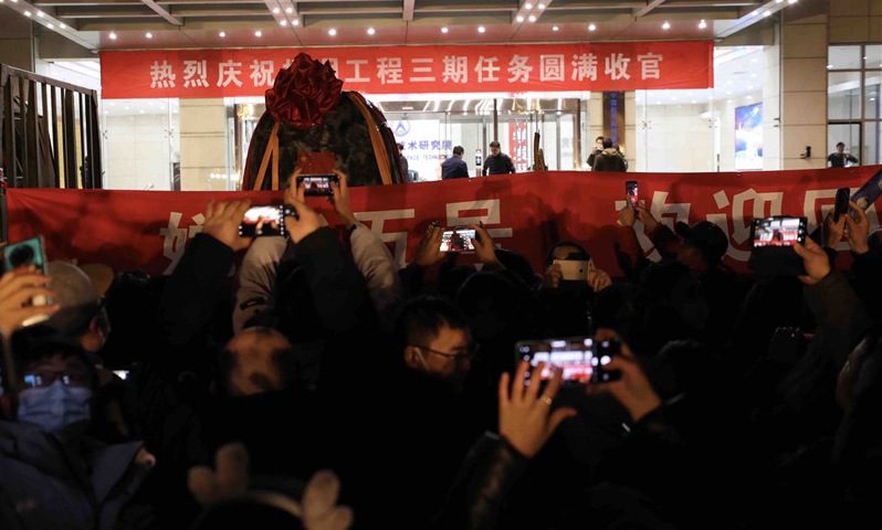 12月17日晚，在完成必要的地面處理工作后，嫦娥五號返回器被空運至北京并正式回到“出生地”——中國航天科技集團五院。按計劃，回收后的嫦娥五號返回器將取出樣品容器及搭載物。國家航天局將擇機舉行交接儀式，正式向地面應用系統移交月球樣品，我國首次地外天體樣品儲存、分析和研究相關工作也將隨之啟動。圖為當晚，在北京中國航天科技集團五院，人們在歡迎嫦娥五號返回器回到出生地。（新華社記者 金立旺 攝）