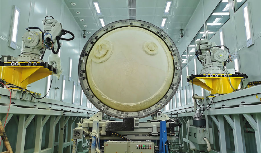 近日，航天科技集團八院149廠低溫貯箱絕熱層自動磨削工藝鑒定方案順利通過工藝評審，并成功應用于運載火箭低溫貯箱研制生產。149廠針對絕熱層手工打磨方式存在厚度波動大、工作效率低等問題持續進行技術創新。據了解，該設備突破了大型貯箱快速掃描建模、橢球形曲面刀具避障路徑編程、大直徑貯箱姿態快速調整等關鍵技術，實現了直徑液氧貯箱箱底和筒段聚氨酯泡沫塑料厚度可控穩定性加工，磨削加工效率可以提高100%以上。圖為低溫貯箱絕熱層正在進行自動磨削加工。