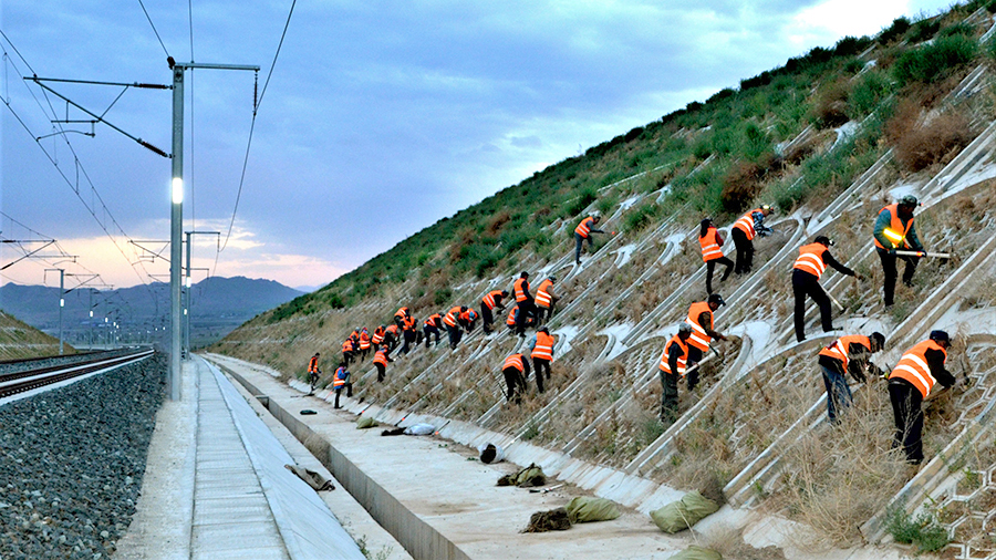 在中鐵二十局承建的崇禮鐵路二標施工現場一派繁忙。彼時，項目參建者正克服既有線施工安全風險大、氣候環境惡劣等困難，補種苗木4萬株，為綠色生態冬奧奠定堅實基礎。圖為參建工人對路基邊坡進行綠植施工。（曲志忠 攝）