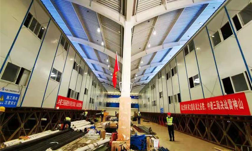 截至1月30日中午12時，雷神山醫院項目總體建設進度完成40％。隔離病房區場地平整、溝槽開挖、溝槽管線預埋、非溝槽區PE膜施工全部完成，溝槽回填已完成90％，條形基礎施工完成60％；集裝箱總計進場1518間，場外改裝完成約300套，現場已完成吊裝30間。醫護人員生活區A1－A7棟完成板房框架梁柱、樓面板、墻面板、屋面板等結構施工的70％。圖為醫護住宿區板房結構施工現場。