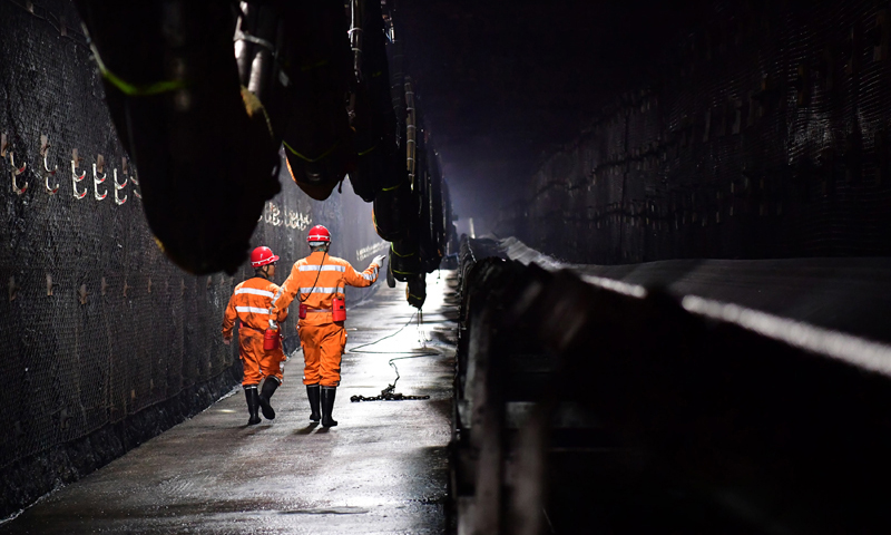 為了駕馭這些“鋼鐵巨獸”，神東煤炭集團派出了一支平均年齡35歲、大專及以上學歷員工占78%的精英隊伍——上灣煤礦綜采一隊。他們通過協作和努力，使上灣煤礦在采煤工效、成本、生產能力、生產安全等方面躋身世界一流水準。圖為11月26日，在上灣煤礦12402綜采面內，工作人員沿著輸送帶進行巡視。（新華社記者 邵瑞 攝）