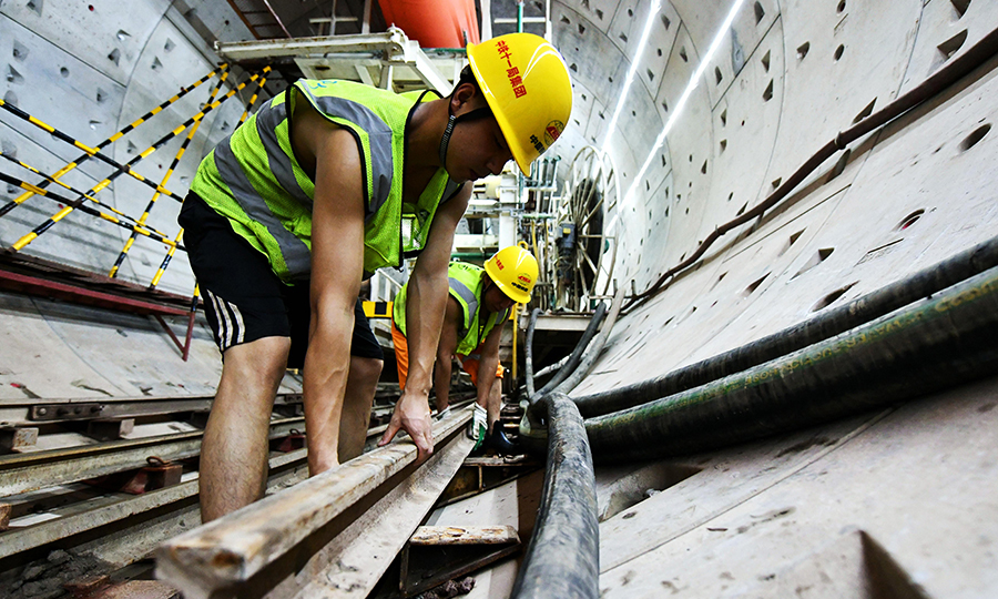 廣州地鐵18號線是全國在建時速最快的地鐵線路，全長約61公里，設計最高時速達160公里。項目建成后，從廣州南沙到廣州東站只需約30分鐘。圖為兩名工人正在轉移盾構電瓶車尾部軌道。