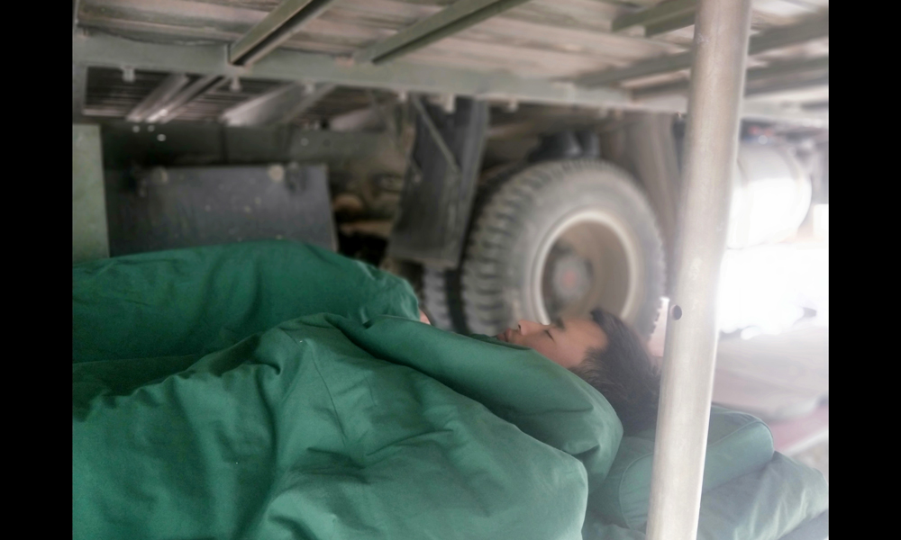 目前，中國安能第三工程局工作人員已奮戰多日，他們不僅晝夜施工，每天二十四小時兩班倒，還要在山里與烈日、冰雨和風沙抗爭，與蚊蟲戰斗。他們不怕吃苦、不畏艱難，用實際行動展現了央企的戰斗精神和過硬作風。圖為6月21日，由于天氣炎熱，夜班人員倒班回來在車底下休息。