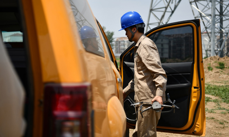 圖為6月24日，電力工人從車上取出無人機準備開始巡檢工作。（新華社記者 李然 攝）