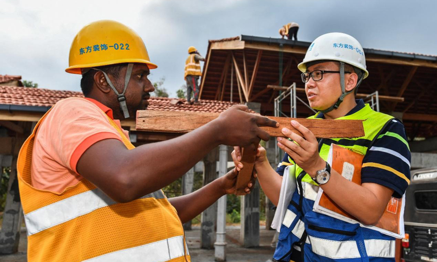 胥超(右)給當地工人的負責人講解木結構的構造原理。