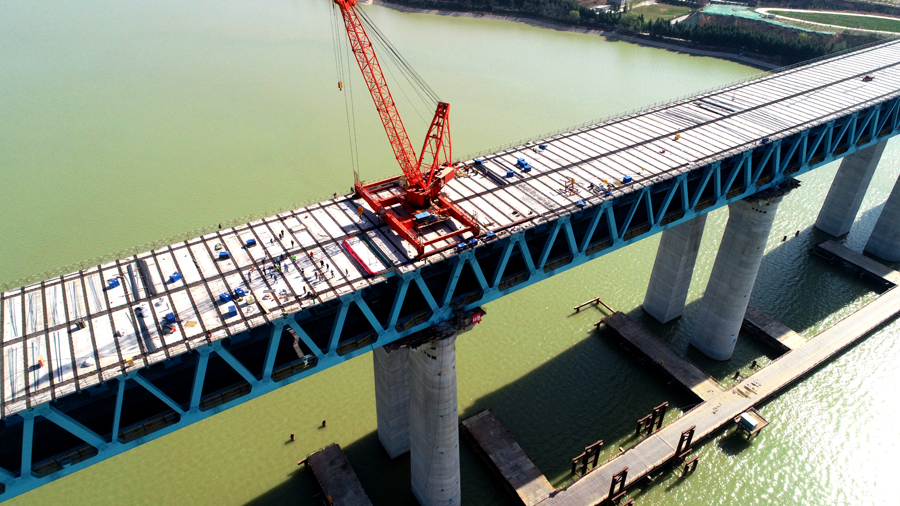 為克服高空作業、橋面板運輸困難、起吊噸位大、施工周期長等不利因素，施工團隊多次召開技術培訓交底會，在鋼桁梁南北兩端分別配備一臺70噸全回轉吊機進行架設施工，安排專人進行現場實時監管，確保安全、質量、進度全面可控。圖為三門峽黃河公鐵兩用大橋公路橋面板架設遠景。