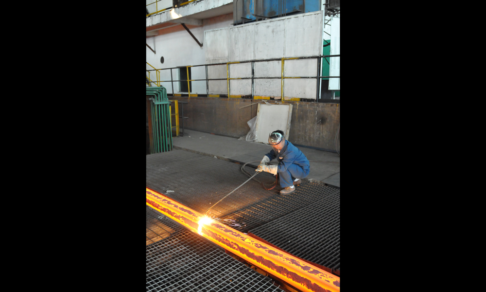 鋼坯冷卻區，青年拉矯工在手動切割鋼坯。（作者：韓先明）
