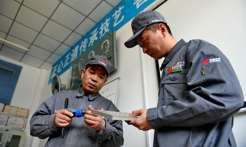4月27日，周晶輝（左）與徒弟臧鐵軍一起研究改進工作中使用的工具。（新華社記者 張楠 攝）