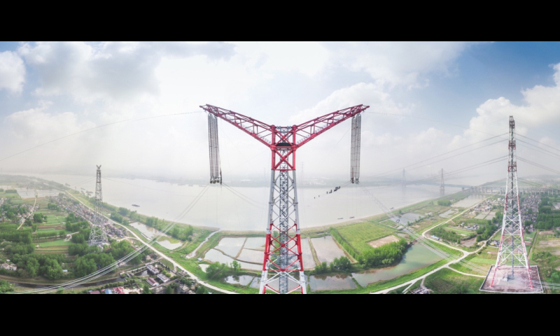 4月15日上午九時許，位于安徽省無為縣高溝鎮的±1100千伏吉泉長江大跨越架線北岸張力場正在緊張施工。一排排導線隨著線盤的轉動在工人們的監視下逐步向長江南岸的牽引場釋放。隨著西電東送±1100千伏“新疆準東—安徽皖南”特高壓直流工程的最后一相導線順利跨越天塹長江，世界電壓等級最高的特高壓大跨越——昌古特高壓長江大跨越工程全線貫通。圖中是導線展放后的昌古特高壓長江大跨越工程北岸跨越塔（無人機拍攝）。