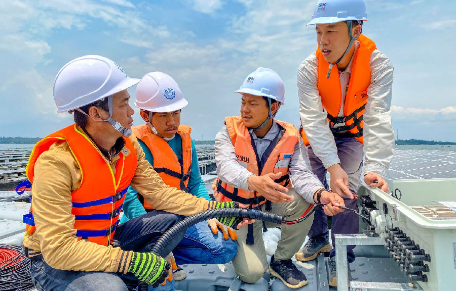 “五一”前夕，中國能建的項目建設工地一片繁忙，有序作業的建設者奮勇爭先，以飽滿的熱情迎接“五一”國際勞動節的到來。為確保工程穩步推進，“五一”期間，中國能建的建設者將全力以赴，奮戰在施工現場。圖為近日，在泰國詩琳通大壩漂浮光伏項目現場，安徽電建二公司技術人員向當地施工人員講解電纜接入的安裝流程與技術要點。