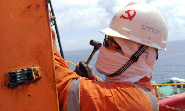 近日，有限公司深圳分公司恩平油田作業區“海洋石油 118”FPSO 的維修人員面對高溫天氣全副武裝防止中暑。圖為一名機械人員在奮力拆卸剎車皮銷軸。