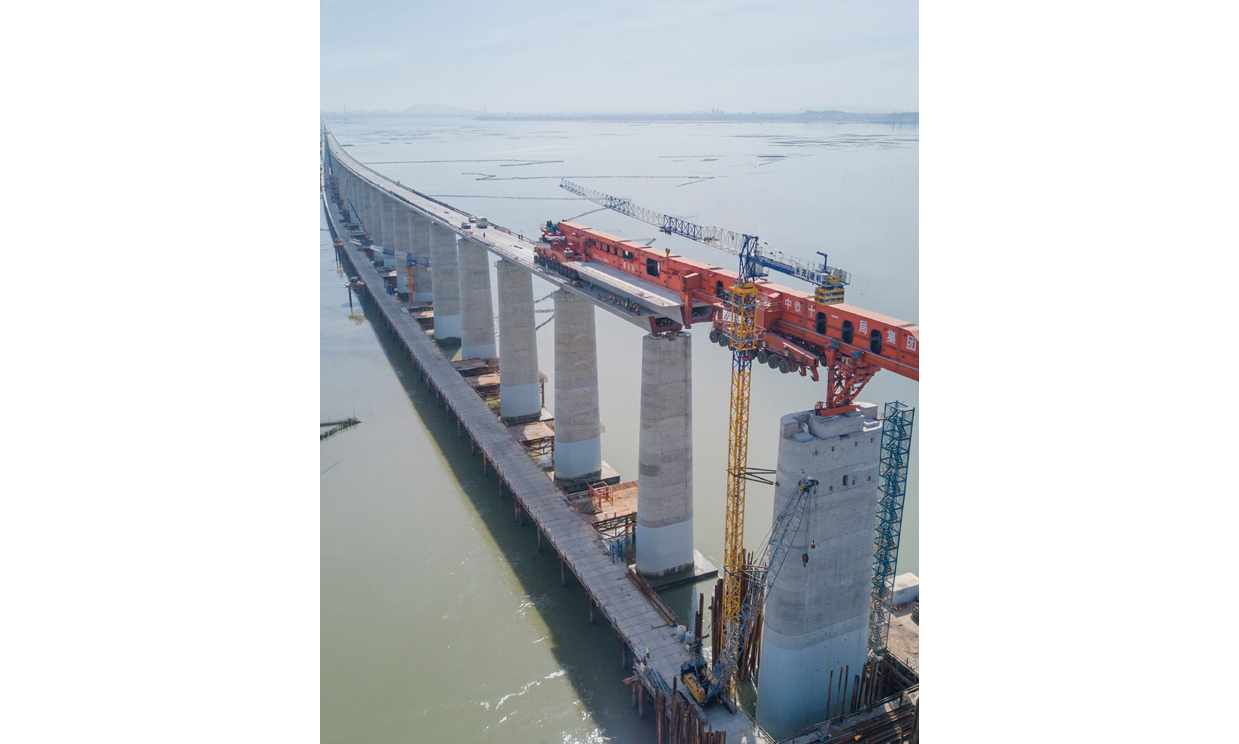 7月11日，我國自主研發的“昆侖號”千噸級運架一體機在中鐵十一局承建的新建福廈鐵路湄洲灣跨海大橋建設現場，圓滿完成最后一孔40米高鐵箱梁架梁任務。接下來，在經過拆解、運輸、組裝之后，這臺體現我國高鐵橋梁架設最先進技術的大國重器將在浙江參與杭衢鐵路的建設。圖為在新建福廈鐵路湄洲灣跨海大橋建設現場，“昆侖號”在架設該線路最后一孔40米箱梁。（新華社記者 宋為偉 攝）
