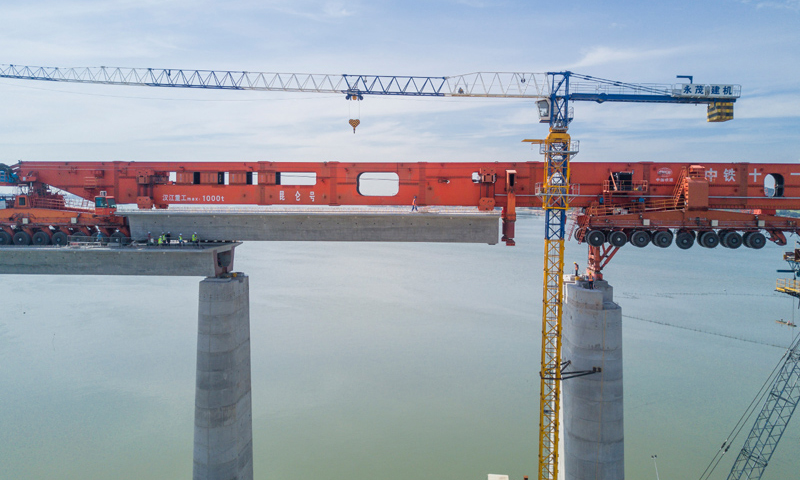 圖為7月11日，在新建福廈鐵路湄洲灣跨海大橋建設現場，中鐵十一局工人協同“昆侖號”千噸級運架一體機架設該線路最后一孔40米箱梁。（新華社記者 宋為偉 攝）