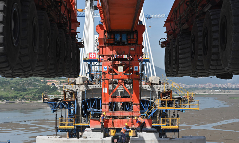 圖為7月11日，在新建福廈鐵路湄洲灣跨海大橋建設現場，中鐵十一局工人協同“昆侖號”千噸級運架一體機架設該線路最后一孔40米箱梁。（新華社記者 宋為偉 攝）
