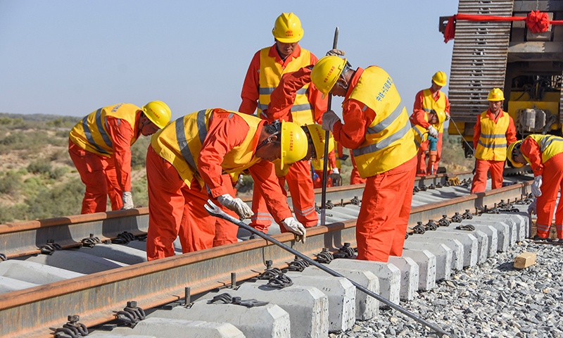 圖為鋪軌完成后工人們進行后續施工。（新華社記者 陶方偉 攝）