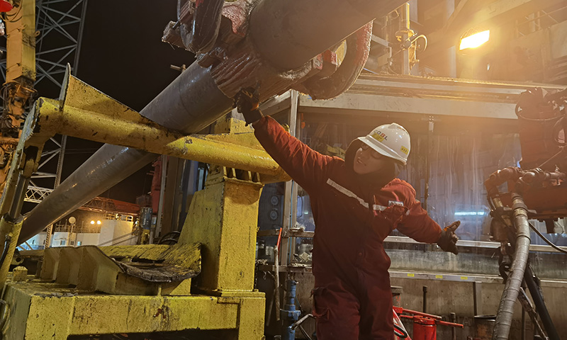 夜晚的鉆臺上，風雪突襲，氣溫接近零下20℃。為保障開發項目安全高效推進，平臺啟動關鍵崗位在崗機制，抓實現場安全管理，作業人員開足馬力全力奮戰下套管作業，助力稠油熱采早日投產。圖為套管作業人員卯足全力扣合吊卡，確保套管入井安全。
