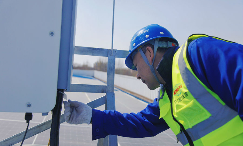 南水北調北京段房橋光伏發電項目位于太陽能資源豐富的北京市房山區，中鐵十四局電氣化公司施工建設者采取“自發自用，余電上網”方式進行設計，并采用全球領先的光伏組件，將太陽能通過光伏組件轉換為直流電，再通過逆變器將直流電轉換成交流電。圖為技術人員檢查現場設備。