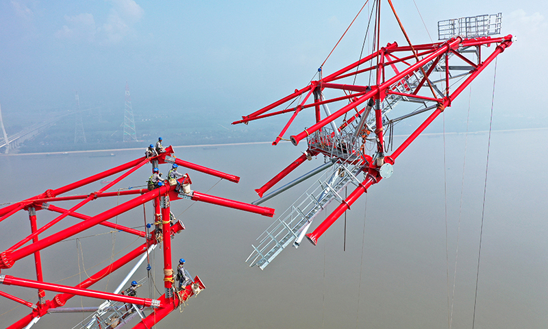 白浙線是我國實施“西電東送”戰略的重點工程，送端連接目前世界在建最大水電站白鶴灘水電站，受端位于杭州臨平區浙北換流站，線路全長2140.2公里。圖為8月1日，安徽送變電工程有限公司施工人員在池州長江大跨越南岸跨越塔封頂施工現場作業（無人機照片）。趙獻富 攝