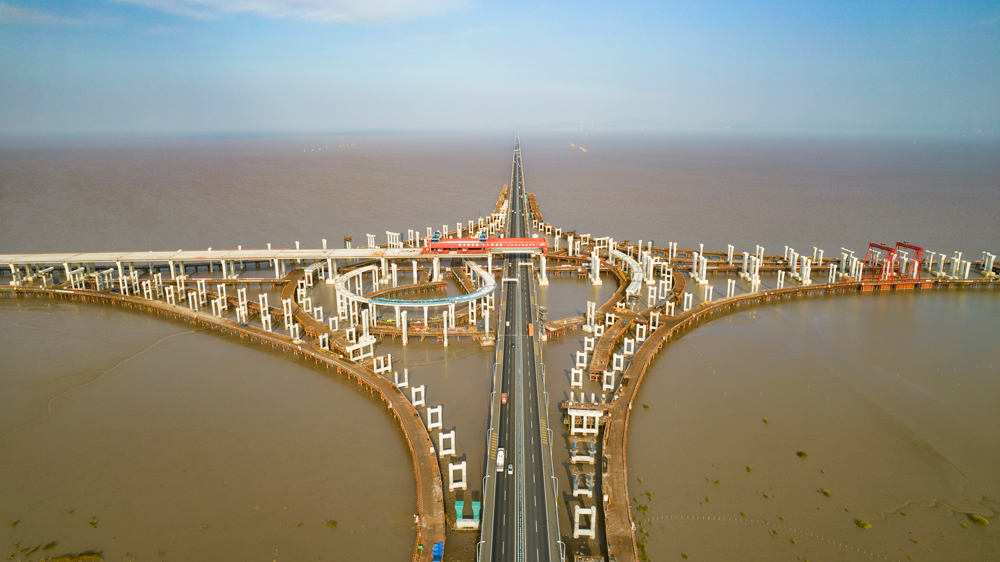 杭甬高速復線寧波一期工程全長55.833千米，為雙向六車道高速公路標準，設計時速120千米。該工程主線橋在寧波市鎮海區一跨直接越過甬舟高速金塘大橋，并設濱?；ネㄅc金塘大橋相接，主線橋箱梁梁底與金塘大橋橋面凈空約7.6米，海上架梁施工安全風險極高，為全線唯一一處Ⅳ級施工風險點。圖為濱?；ネㄖ骶€橋跨越金塘大橋架梁現場。