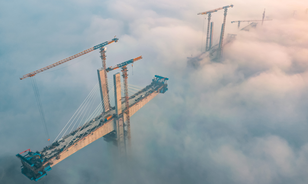 11月15日，大霧籠罩，在渝昆高鐵（川渝段）重點控制性工程——瀘州沱江特大橋項目建設現場，中國中鐵旗下中鐵四局建設者在100余米的高空進行斜拉索掛索及懸臂節段掛籃懸澆作業。