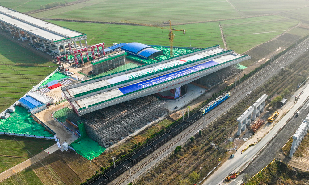 跨京滬鐵路轉體橋上部結構采用預應力混凝土T構，跨徑組合為（68+68）米，下部結構主墩采用“V”型空心墩設計，整幅橋梁全寬38.33米，轉體重量高達25680噸，主承臺深基坑開挖處臨近繁忙干線京滬鐵路，距路基坡腳線最近處僅有15米，臨近鐵路基坑開挖深度10余米，施工過程復雜、精度要求高。圖為轉體橋轉體中。