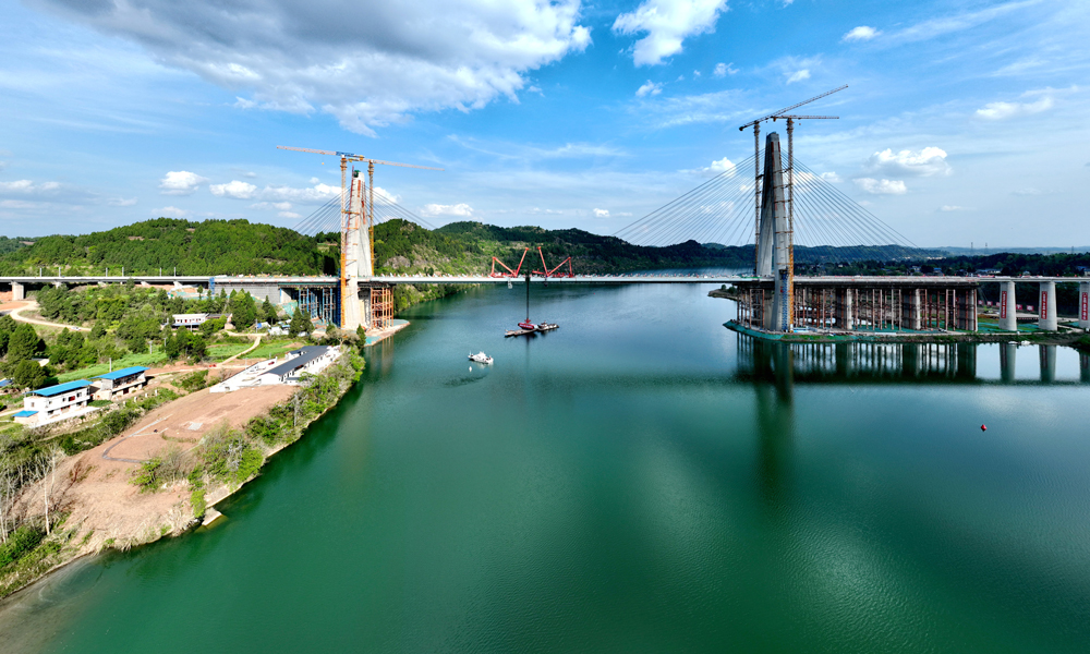 其中，嘉陵江特大橋全長1770.82米，大橋主跨335米，是目前我國在建跨度最大的雙線高速鐵路高低塔混合梁斜拉橋，橋塔呈“鉆石型”結構，雙塔高分別為164.5米和120米，分別通過64根、44根高強平行鋼絲斜拉索，共同支撐起大橋主梁。圖為大橋航拍側景。