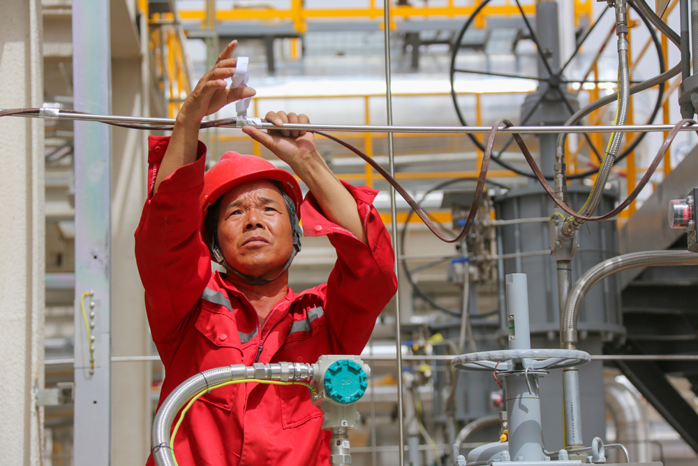 順北油氣田地處塔克拉瑪干沙漠腹地，6月以來該地頻發高溫紅色預警。西北油田采油四廠啟動高溫應急預案，干部員工克服高溫風沙天氣，堅守在上產一線，確保油氣井生產安穩運行。圖為近日，天然氣處理廠維護人員為設備加裝電伴熱。