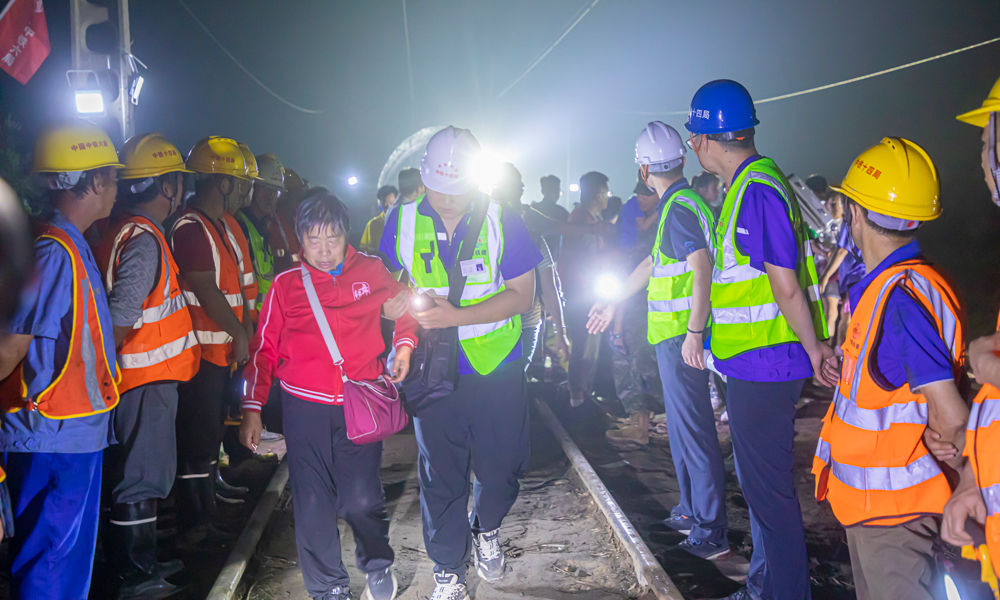 8月2日19時，中鐵十四局京唐項目、北京地鐵17號線項目80余名工作人員兵分兩路，一部分工作人員搬運枕木，重修鐵路路基；另一部分工作人員背靠坍塌部分路基，形成愛心人墻，協助被困Z180列車503名乘客解除困境。侯慧 攝