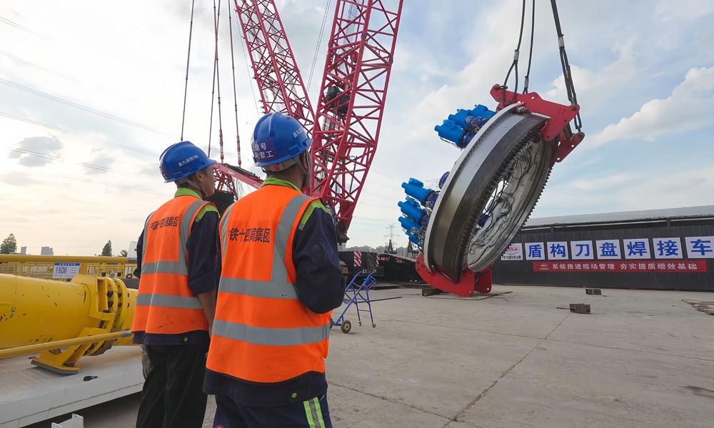 為確保10月底盾構始發這一重大節點，300多名施工人員在節日期間堅守崗位，奮戰在一線。該隧道全長6.379公里，采用“盾構+明挖”進行施工，其中盾構段長4.4公里。圖為施工人員為主驅動下井做準備。