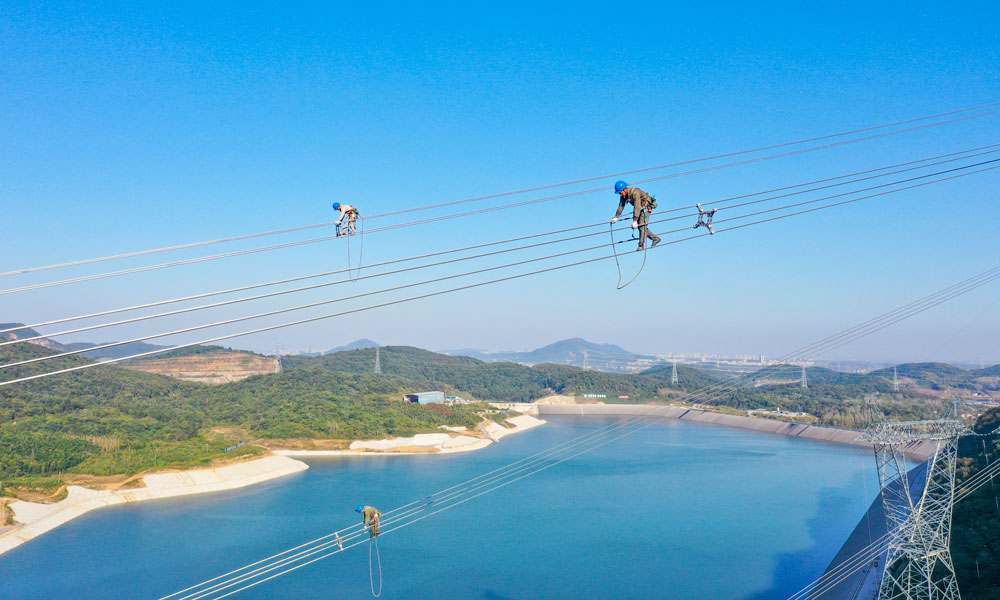 國家電網江蘇省送變電有限公司輸電人員在高空走線驗收消缺。