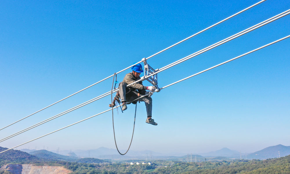 國家電網江蘇省送變電有限公司輸電人員在高空走線驗收消缺。