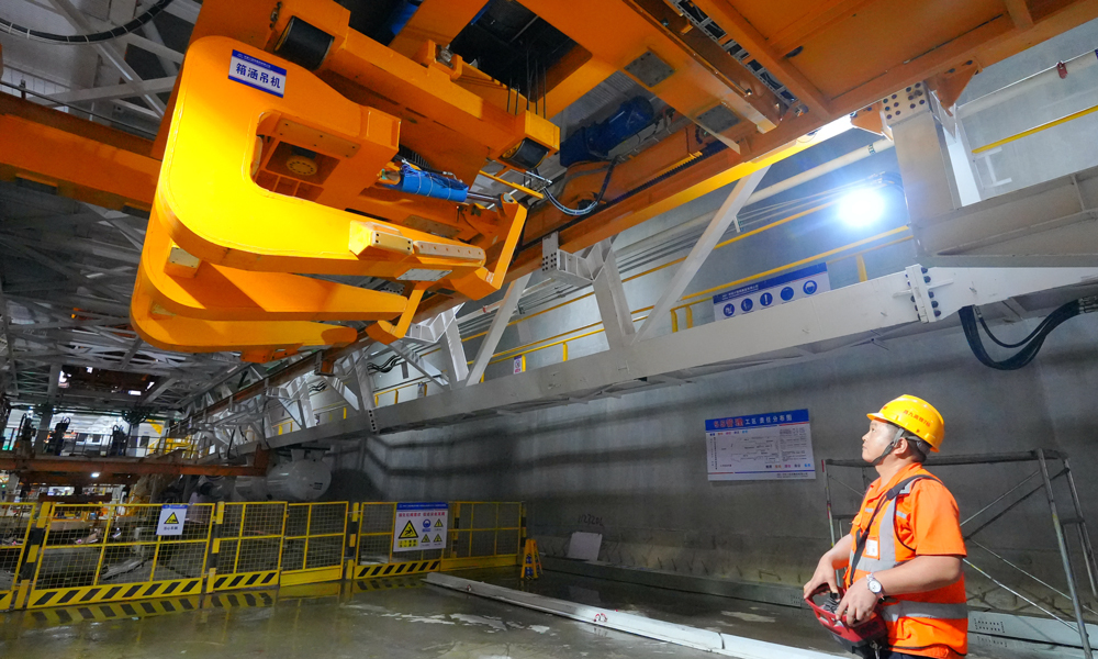 針對首次在350公里高鐵隧道使用“整體全預制箱涵”，項目團隊升級優化盾構機箱涵吊裝設備，實現箱涵件自動抓取、一鍵調平工藝，將極大節省后續同步施工量，減少安全隱患，提高工程質量和效率。圖為建設者正在操作箱涵吊機。