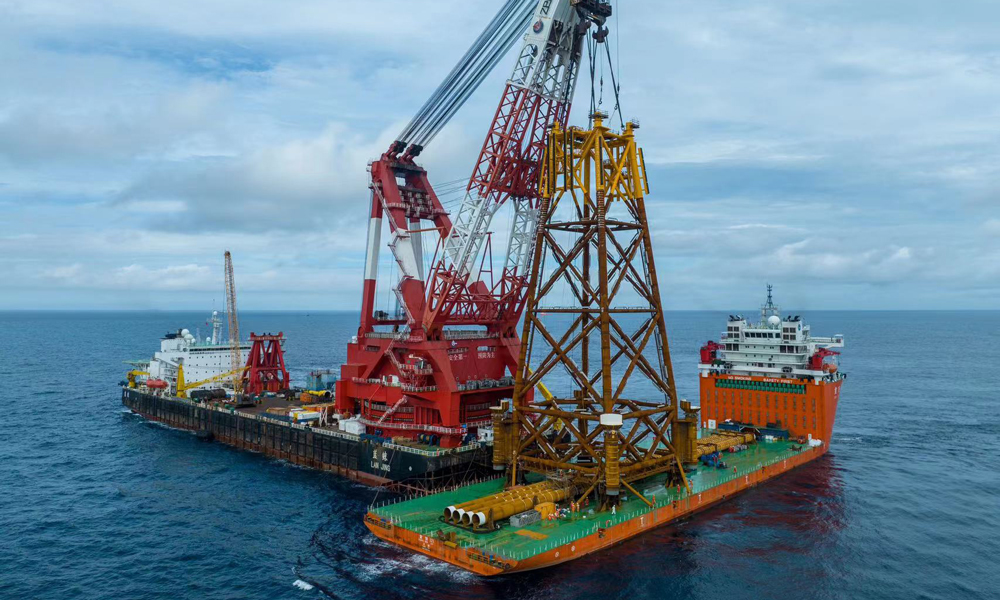 如何在短時間內將觀測平臺精準安裝至設計坐標點位，對吊裝操作和現場指揮提出嚴峻挑戰。針對觀測平臺結構特點以及安裝海域復雜的水動力環境，項目團隊調配了亞洲頂級的海洋工程船舶 ——“藍鯨”號現場施工。面對吊裝重量達2080噸、高度達77.7米的導管架，采取“垂直起吊、垂直下放”的超高空作業方式，僅用半天時間就完成吊裝下水并精準就位。圖為“藍鯨”號完成觀測平臺導管架掛扣。