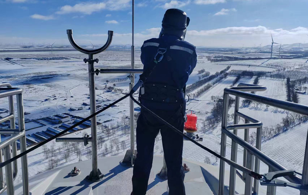 近期，寒潮天氣持續影響多地。東方電氣集團持續推動能源工程項目進度，做好項目現場保障服務，助力能源保供。圖為在河北省馬神梁風電項目現場，東方電氣集團現場調試人員站在高達百米高的風機上檢查風速儀和風向標，確保風機安全運行。