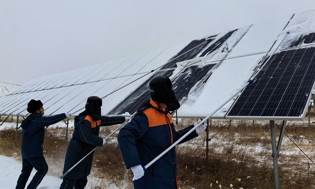 中廣核山西右玉風(fēng)光互補(bǔ)電站作業(yè)人員清除電站周邊通道及光伏板上的積雪。