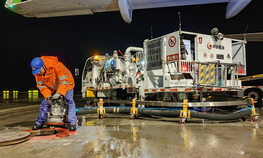 中國航油貴州分公司航空加油站飛機加油員進行雨中加油作業。