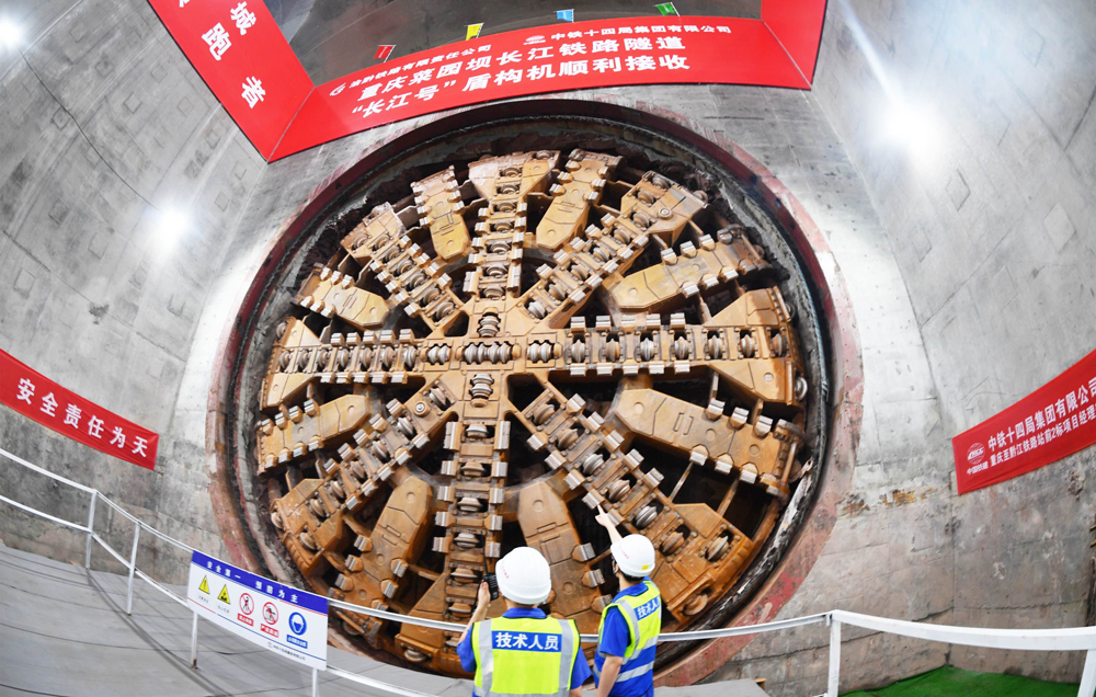 重慶菜園壩長江鐵路隧道是渝廈高鐵全線關鍵控制性工程。隧道位于重慶市渝中區與南岸區，為單洞雙線高速鐵路隧道，全長11942米，起始于重慶火車站，沿途下穿市政道路、高架橋梁、軌道交通線、多處建筑群、長江主航道及南山山體，整體呈現“穿山、穿城、穿江、穿水”的復雜特點，施工難度大、技術要求極高。圖為技術人員檢查刀盤磨損情況。