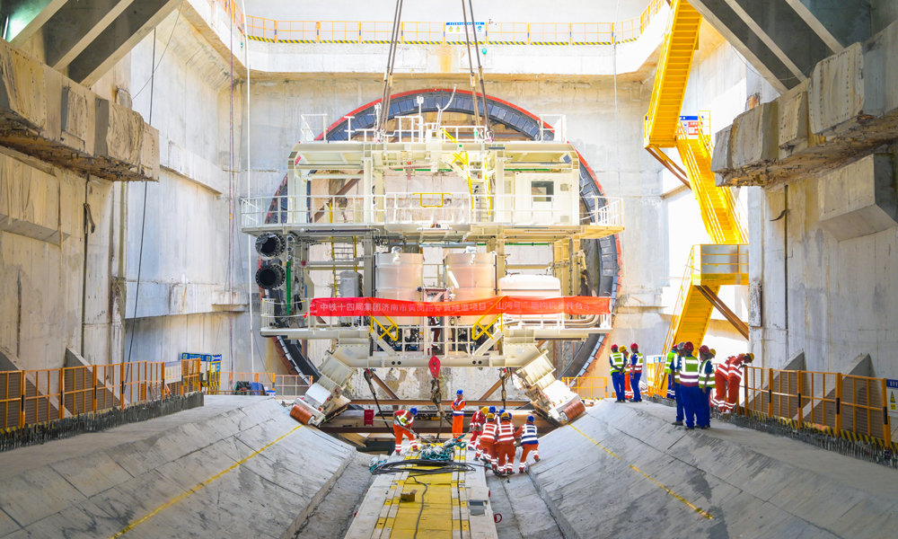 濟南黃崗路穿黃隧道工程是構建南北向跨黃河的大通道之一，建成后，將助力濟南主城區(qū)與新舊動能轉換起步區(qū)互聯(lián)互通，有力推進起步區(qū)建設全面提速，促進濟南從“大明湖時代”邁向“黃河時代”，為黃河流域生態(tài)保護和高質量發(fā)展提供有力支持。圖為始發(fā)井內，盾構機臺車吊裝到指定位置。