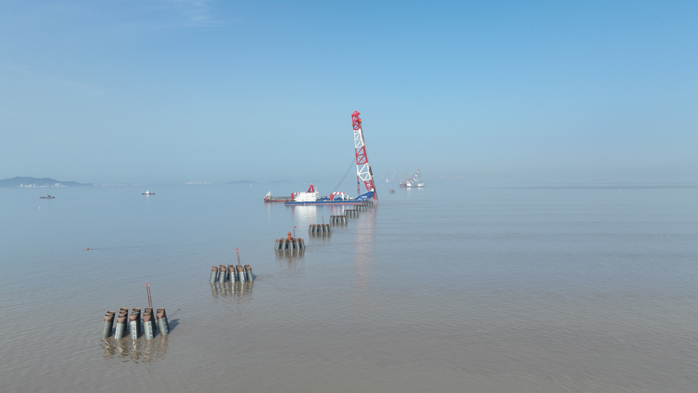 近日，由中交集團所屬二航局投資打造的全球最大打樁船“二航長青”亮相東海，將一根長98.5米的鋼管樁精準釘入海底巖層，助力杭州灣跨海鐵路大橋步入建設快車道。