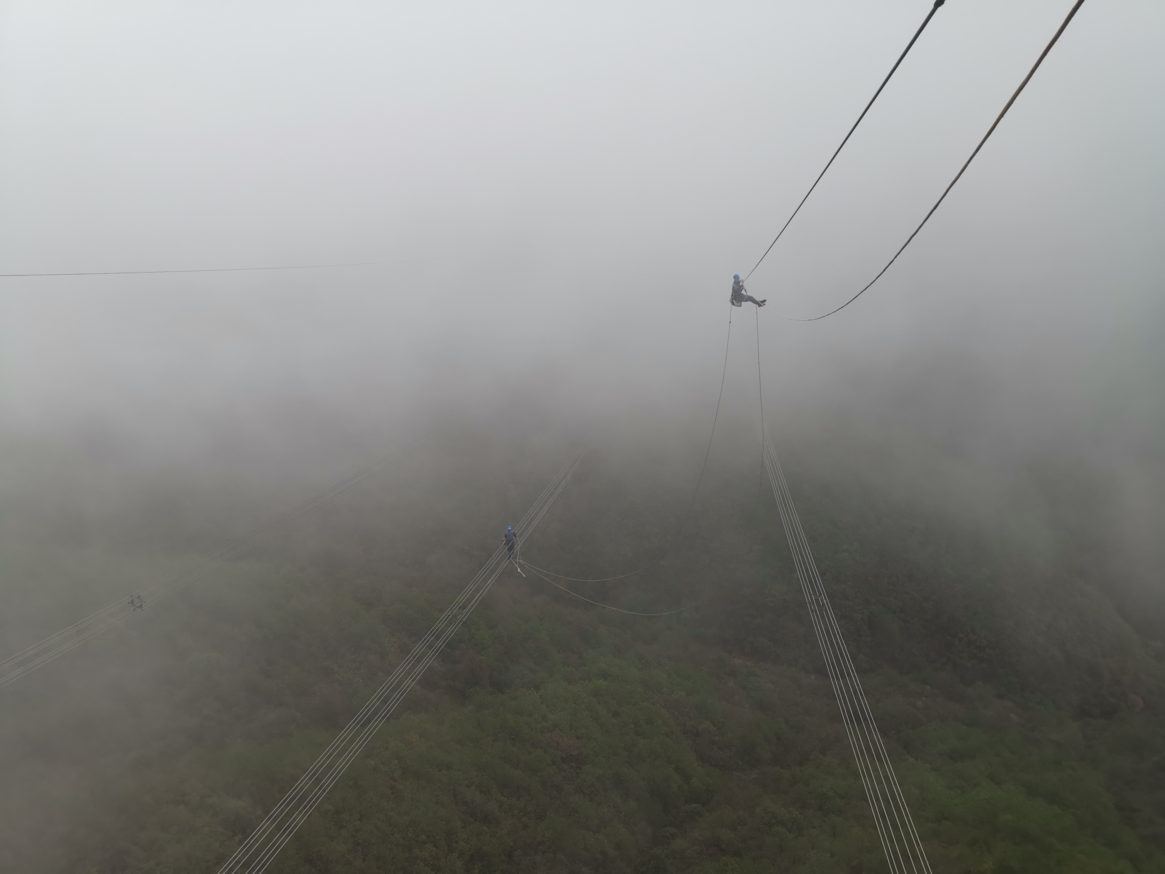 11月24日，超高壓柳州局工作人員方守剛坐飛車在架空地線上懸空工作，導線上作業人員唐瑞焱，開展桂山乙線55#大號側架空地光纜補強工作。（韋志勇）.jpg