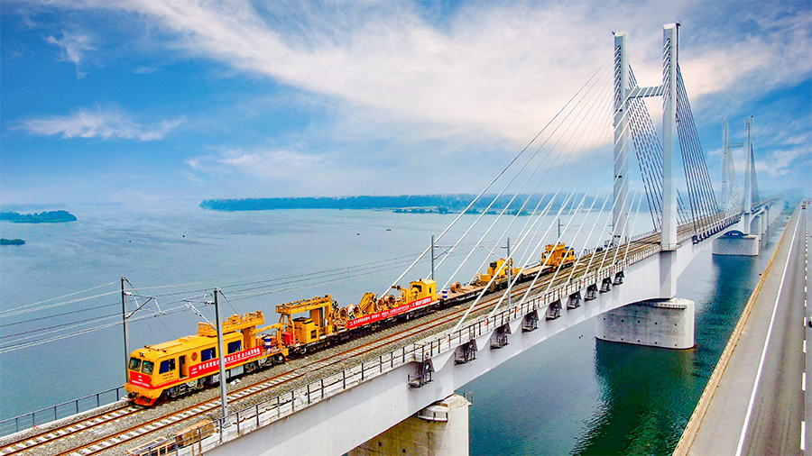 9月28日早上6時30分，首趟105節貨運列車滿載8400噸煤炭從浩勒報吉南站駛出，標志著世界上一次性建成并開通運營里程最長的重載鐵路——浩勒報吉至吉安鐵路（以下簡稱浩吉鐵路，即原蒙西至華中地區鐵路）開通運營。浩吉鐵路全長1813.5公里，北起內蒙古鄂爾多斯市浩勒報吉南站，終到京九鐵路吉安站。它的開通，改變了中國鐵路煤炭運輸格局，為我國鐵路版圖新增一條縱貫南北的能源運輸大通道。圖為中國鐵建電氣化局浩鐵路漢江特大橋上接觸網軌道車施工。