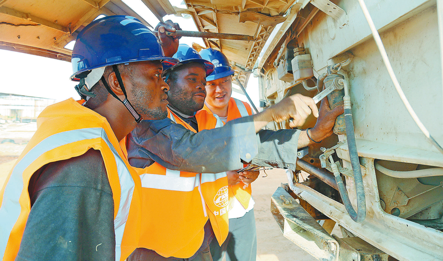 在安哥拉二期大市政項目建設中，為確保工程如期履約，中國鐵建所屬中鐵十四局通過開展技術革新、提高機械設備能效、大量聘用當地工人等措施，既加快了工程進度，又節約了施工成本，為解決當地就業、加快經濟發展作出了積極貢獻，贏得了當地居民和政府的好評。圖為當地時間10月28日，安籍員工在中方技術人員指導下檢修施工車輛。（周存泉 攝）