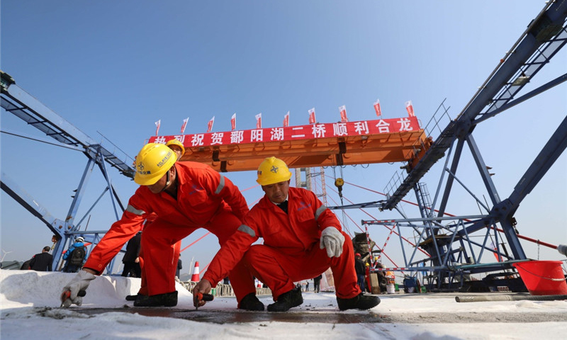 圖為11月28日，兩名工人在鄱陽湖二橋橋面上進行收面施工。新華社發（韓俊烜 攝）