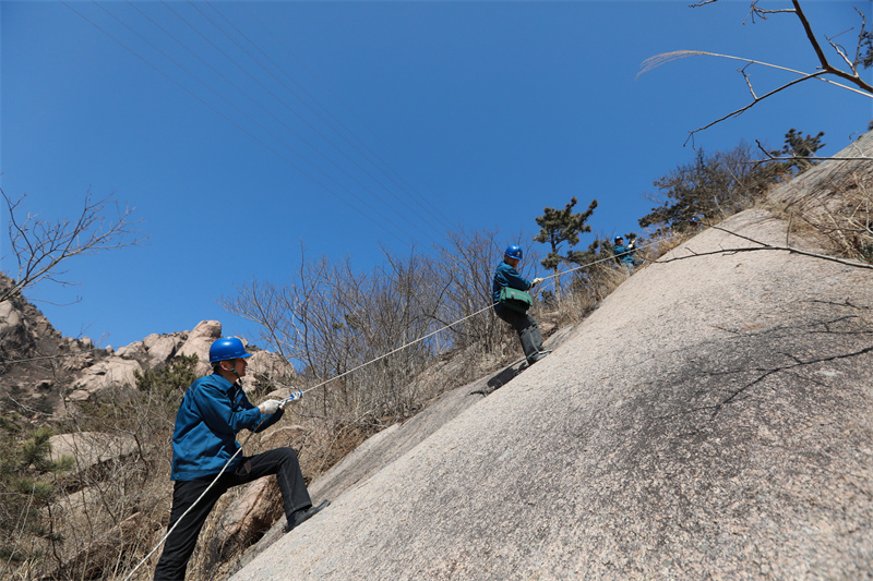 3月16日，山東榮成市供電公司員工對槎山上的電力線路進行特巡。坡度較大的山坡，巡檢人員需要借助繩子上下。.jpg